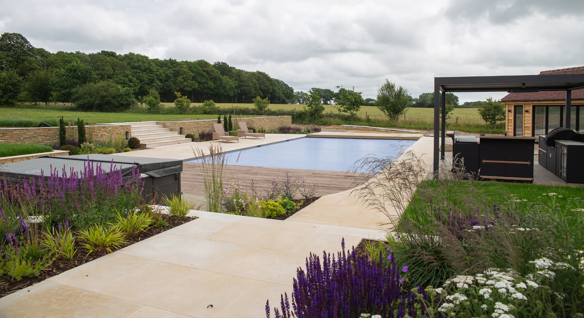 High-end poolside terrace in natural stone with dry stone walling and mature planting