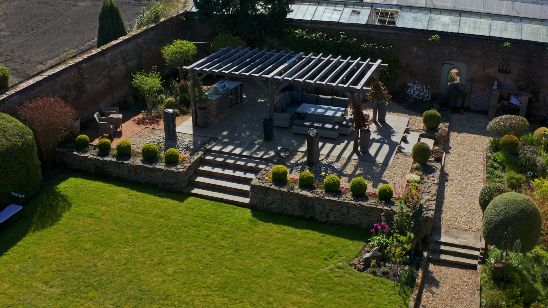 Luxury outdoor living space with a pergola, outdoor kitchen, seating terrace and manicured lawns