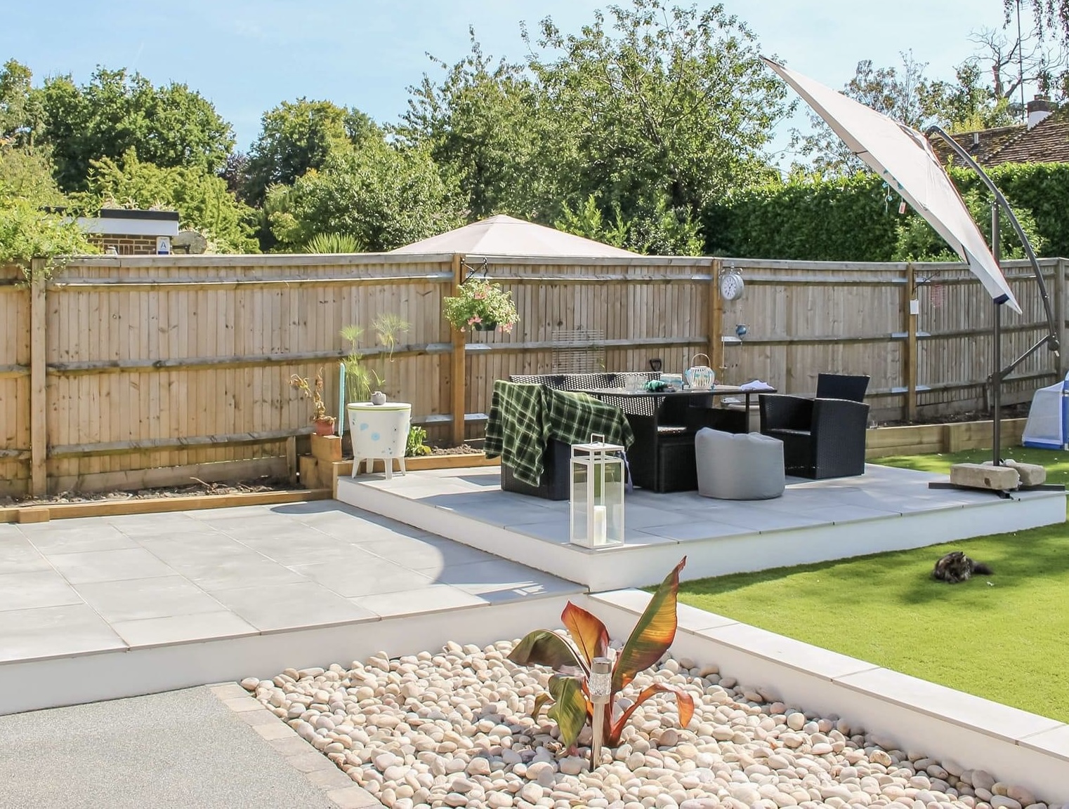 Premium porcelain terrace with a dining area, pebble bed and precisely finished lawn