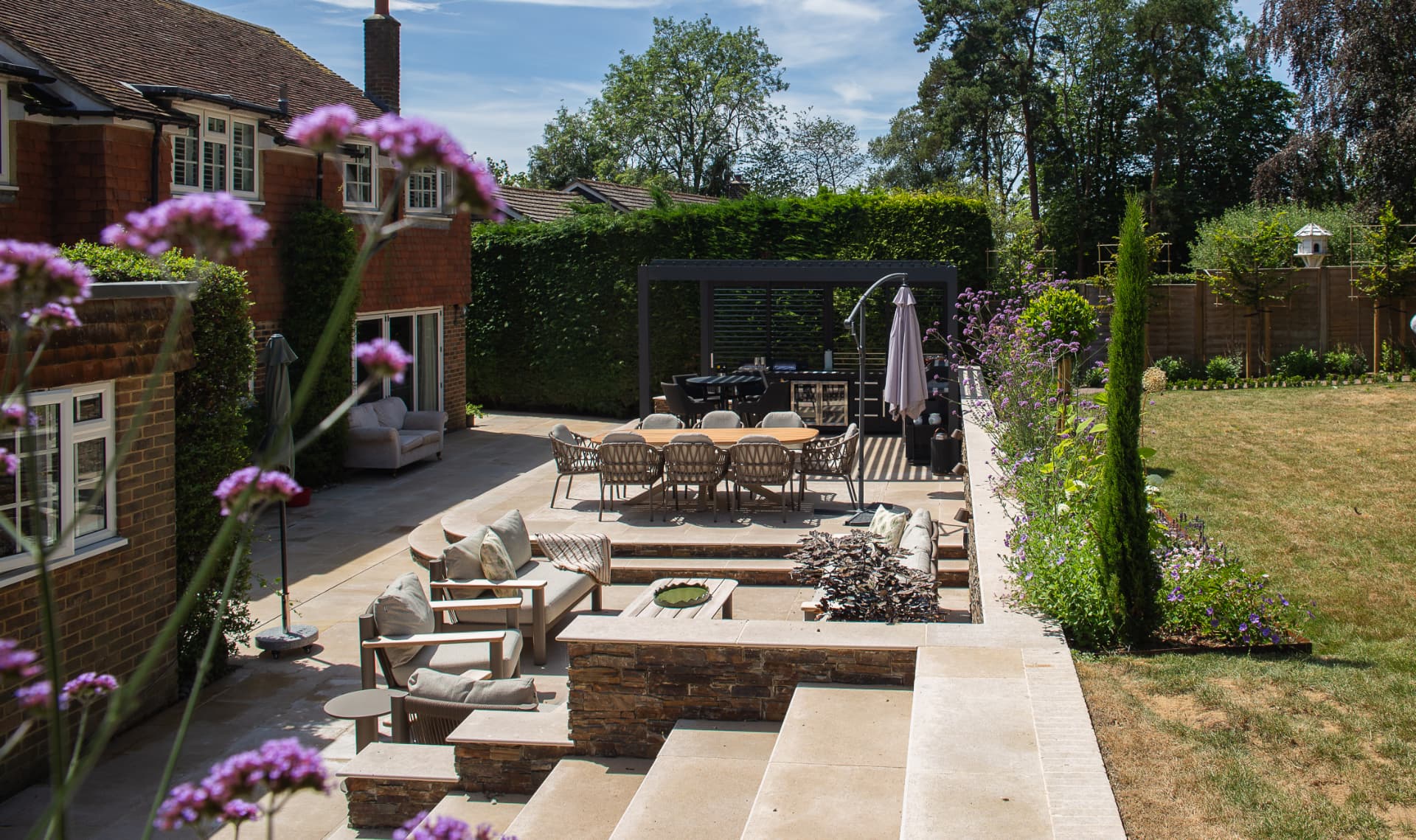 Luxury landscaping with a sunken sandstone terrace, built-in seating, steps and a pergola dining area
